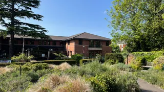 View of the Rose Garden with a variety of plants, Three Rivers House in the background