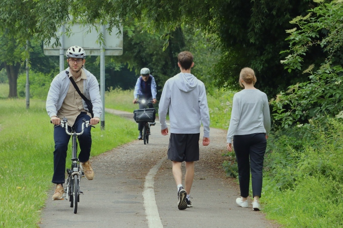 Two cyclists in a cycle lane passing two people walking on the pedestrianised part of the path.