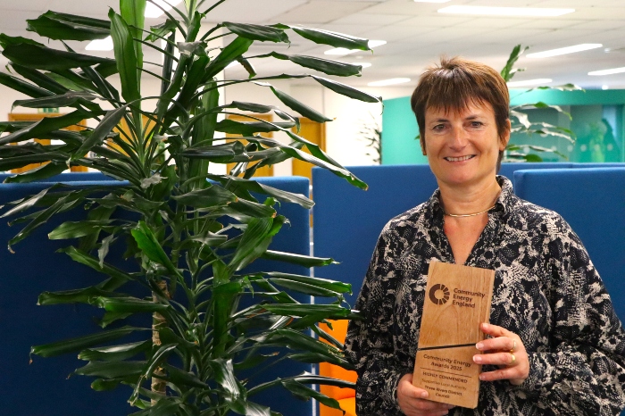 Jo Hewitson holding the wooden community energy England award