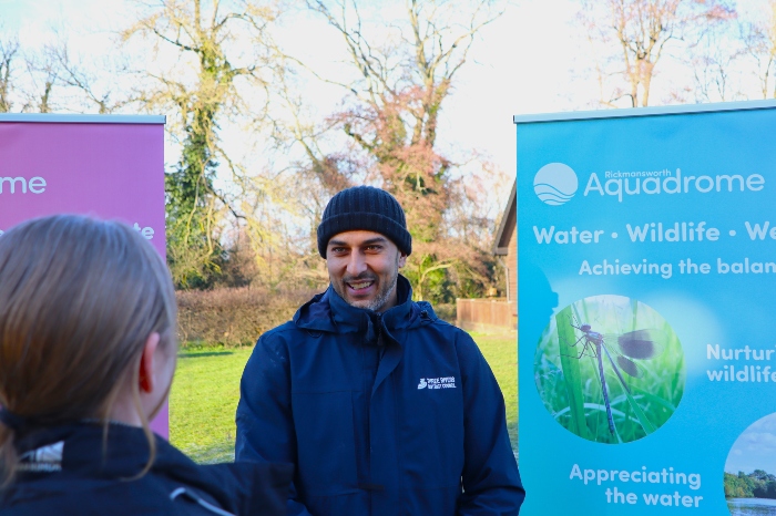 Marcus Day speaking to a member of the public. He is standing next to roll-up banners that show pictures of the Aquadrome